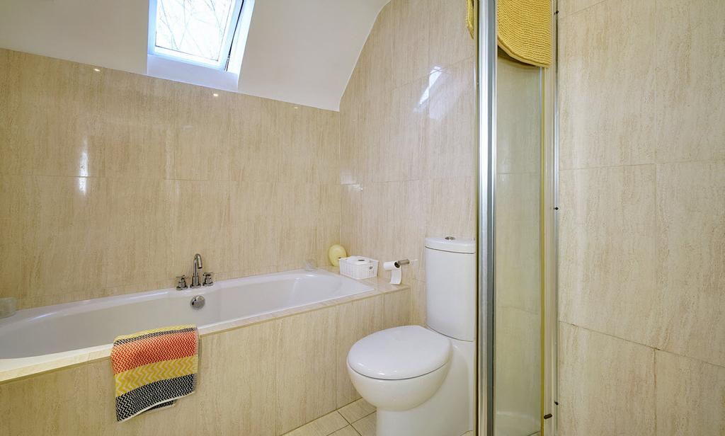 BATHROOM: Modern white bathroom suite comprising tiled panelled bath with
