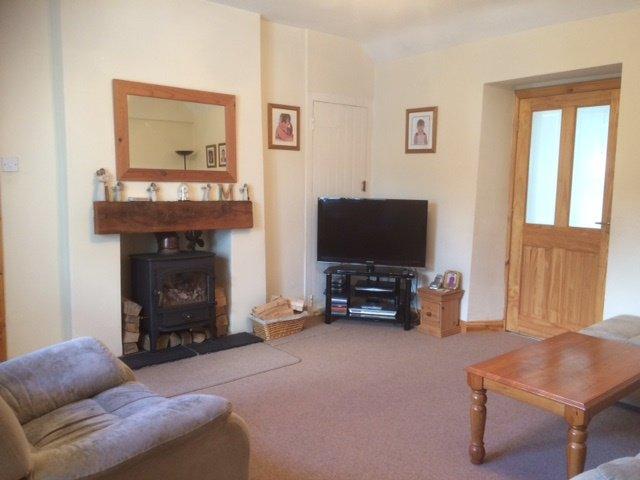 50) Wood burning stove set on tiled hearth with solid wood mantle. Storage cupboard to side. Window to front. Radiator. 4 double sockets. T.V. point. Telephone socket.