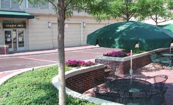 Metal fencing between brick piers, in combination with shade trees, screens this surface parking lot.