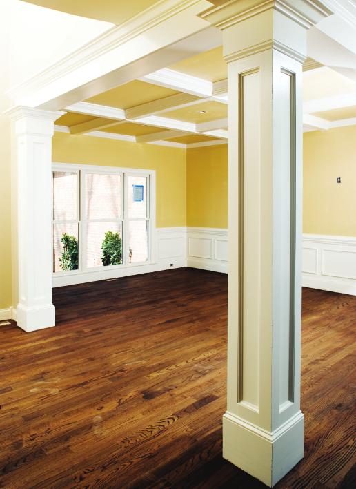 RealityHome Building Walnut-colored hardwood floors contrast with the blonde walls to add luxury to the