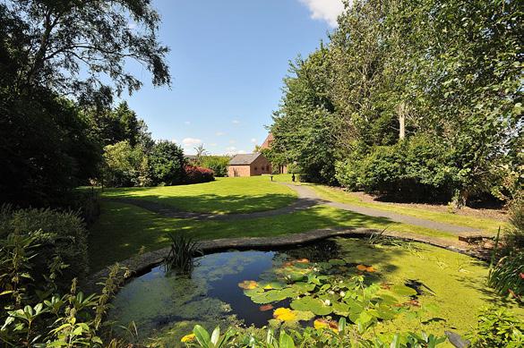 in a generous plot of beautifully landscaped gardens, comprising of large flat lawns, stone flagged patios and attractive