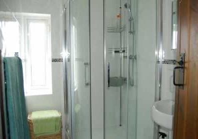 TILED THREE-PIECE SHOWER ROOM White suite comprising large corner shower stall with shower (water comes from the tower roof