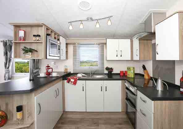 The kitchen includes raised work surfaces and contrasting cupboard doors, plus an integrated fridge freezer, oven and grill,