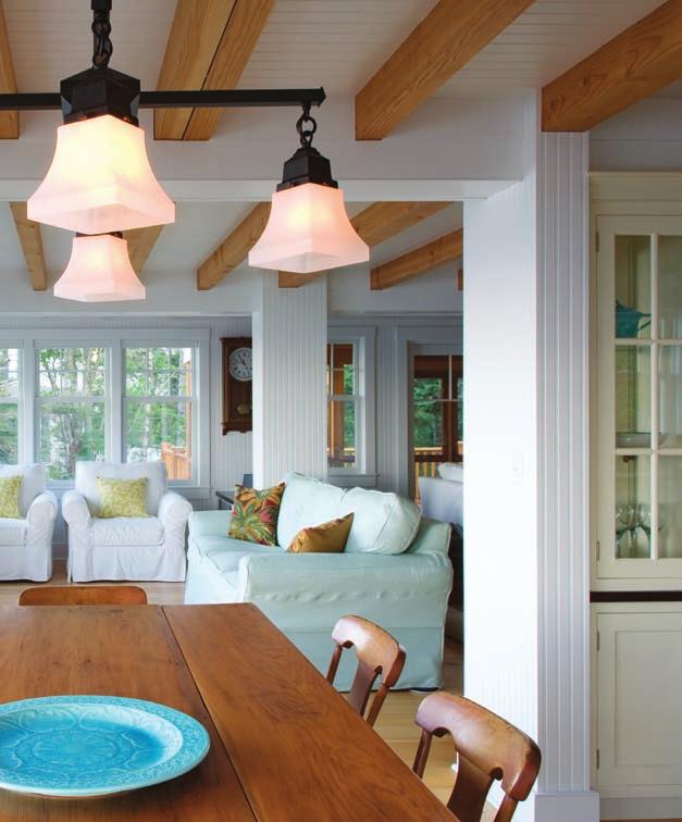 The use of wide, tall windows to let in light opens the room to the outside. White walls and upholstered furniture give the home an airy look, common in farmhouse style.