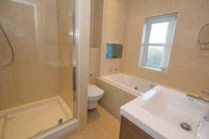 11m (8'1" x 6'11") Refurbished with a modern white suite comprising tile panelled spa bath with recessed tv screen, tiled shower enclosure with glazed screen, vanity wash basin with mixer tap and all