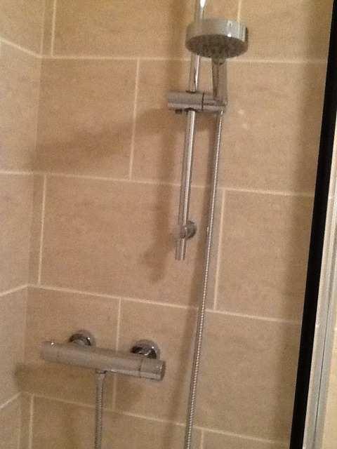 Wall mounted chrome shower fixing with chrome shower hose, head and riser. Glass screen with chrome edging, smear free.
