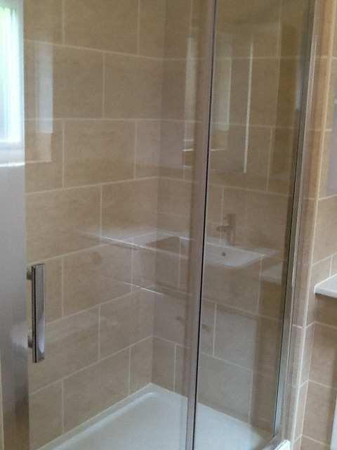 Comparison En-suite - Bath/Shower En-suite - Bath/Shower Chrome framed glass sliding door shower cubicle, fitted to a white fronted