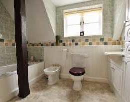 Panelled bath, close coupled wc, bidet and vanity wash hand basin with storage units below and mirror and light/shaver point above. Attractive tiling to the walls with a decorative border tile.