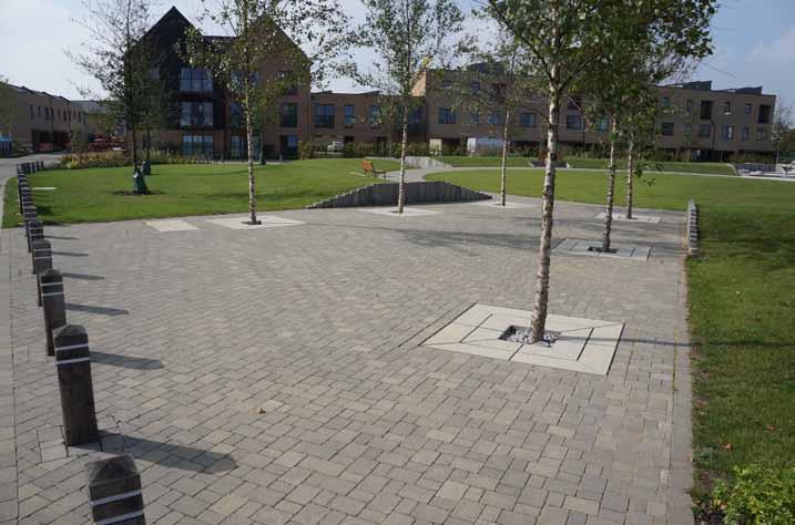 Block paving runs from building to building across mews streets with planting areas contained by concrete kerbs.