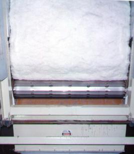 Cotton flows from the battery condenser into the Steamroller. Taming a thick, fast moving fluffy batt of cotton is no problem for the large feed-in drum.