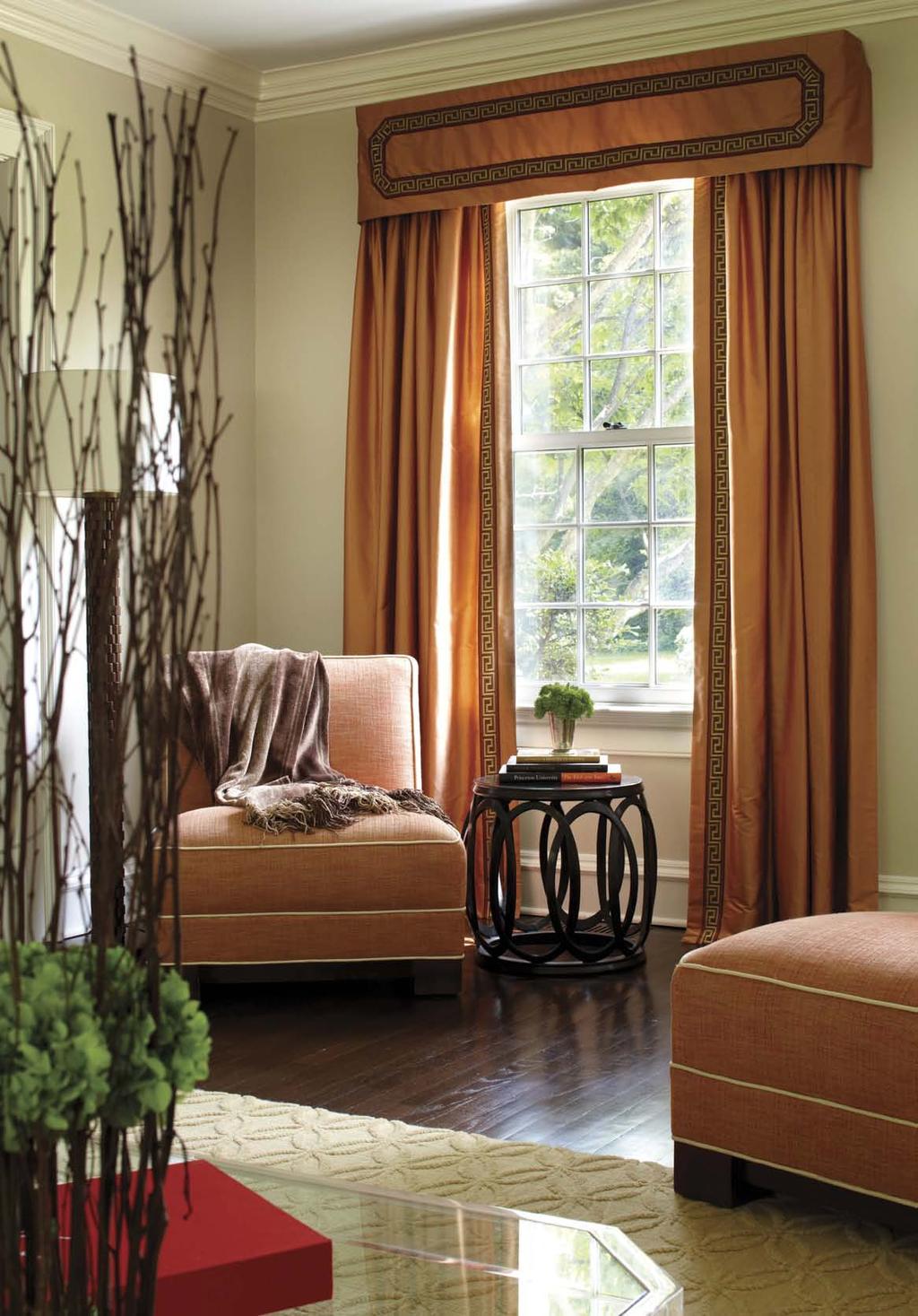 Luxurious silk drapery panels in a vibrant shade of orange dress the windows in the living room.