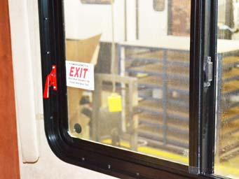 SECTION 2 SAFETY AND PRECAUTIONS Escape Window (Lift both red safety latch handles UP and push window OUT) -Typical View