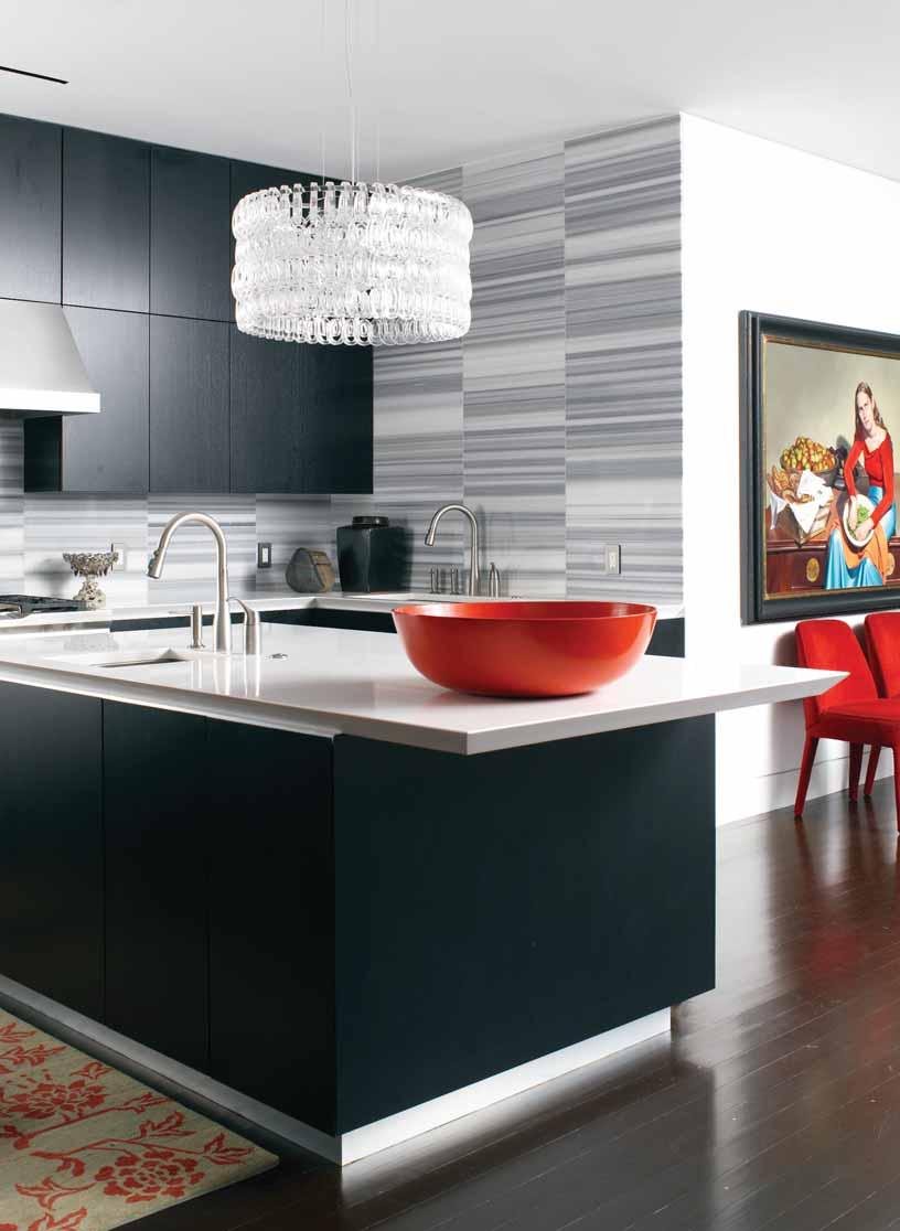 The sleek kitchen gets a dose of drama from a Lucite chandelier. The painting next to the kitchen is by designer Jeanne Duval.