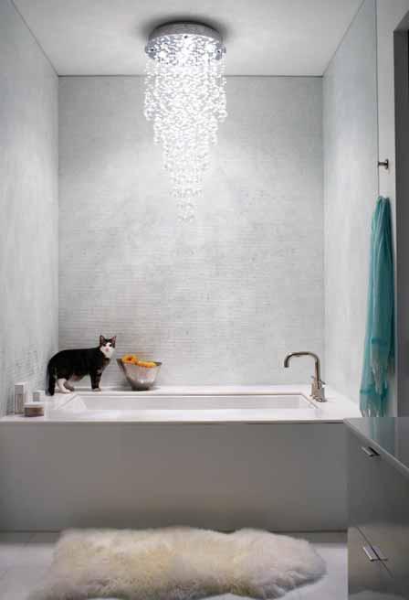 Tiny iridescent tiles glow in a rainbow of pale pastels under a shower of light. with its white Silestone countertops and walls of marble tile with horizontal stripes in shades of gray.