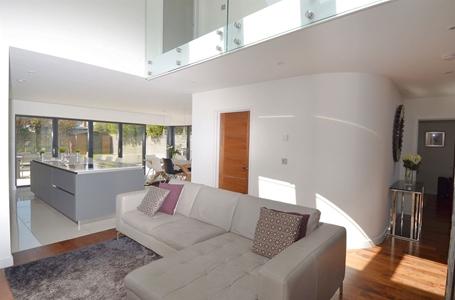 sitting area and family area share a double sided log burner with the family area sitting beneath a vaulted ceiling and opening to a large spectacular kitchen/dining room with a complete wall banked