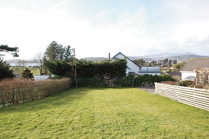 Area of gravel. Wooden gate gives access to the rear garden. The rear garden is laid mostly to lawn and enjoys excellent views towards the estuary.