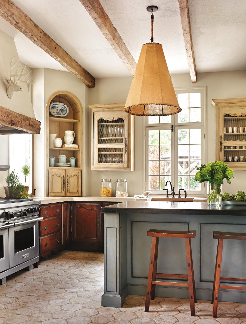 THIS PHOTO: Reclaimedwood ceiling beams, glazed upper cabinets with chicken-wire insets, and limestone countertops lend patina to the remodeled kitchen.