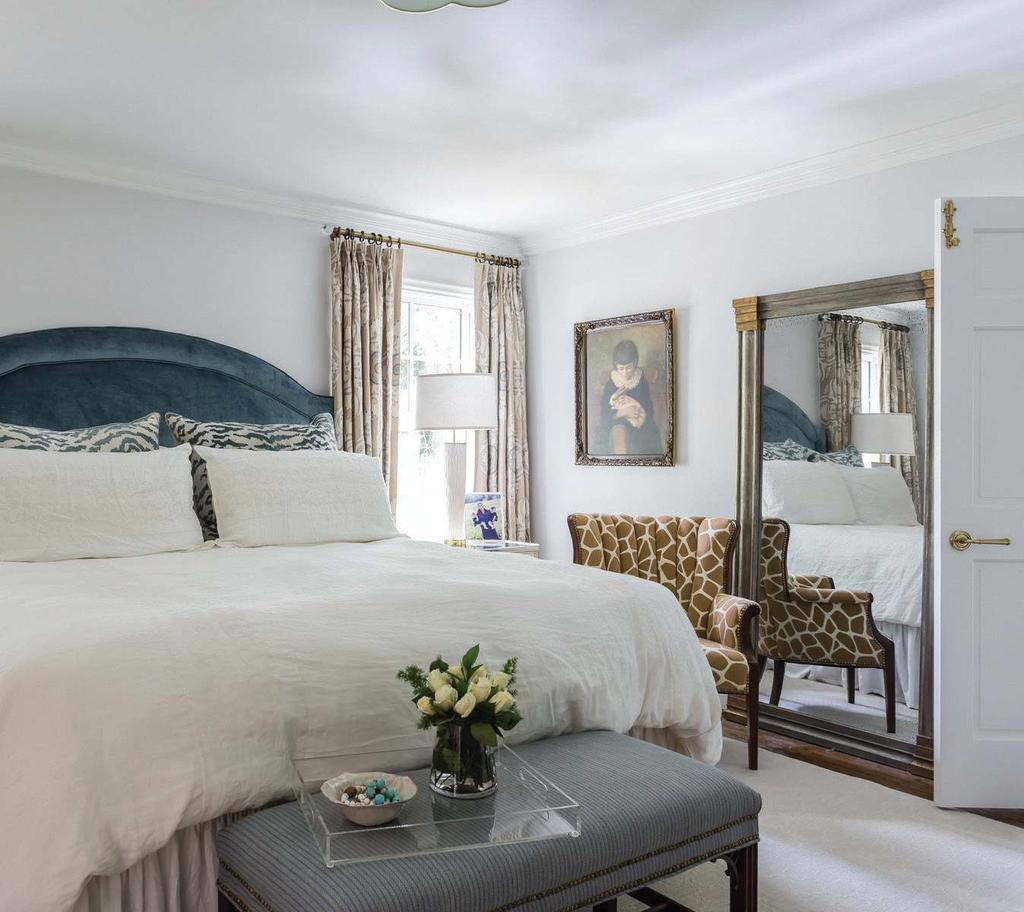 A custom blue velvet headboard, embroidered appliqued linen drapes by Cowtan & Tout, a bench covered in Designers Guild fabric, and zebra-print shams by Thibaut all add luxurious texture and