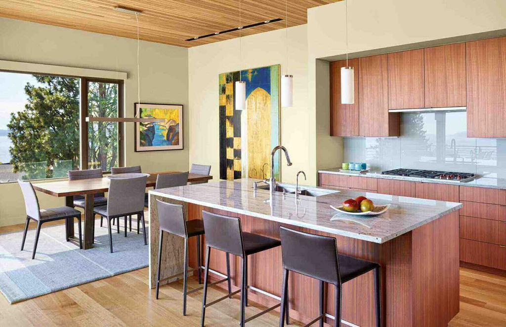 Arper stools from Inform Interiors provide seating in the kitchen, which has been outfitted with a Wolf cooktop from Arnold s Appliance and sapele cabinetry fabricated by Cornerstone Fine Woodworking.