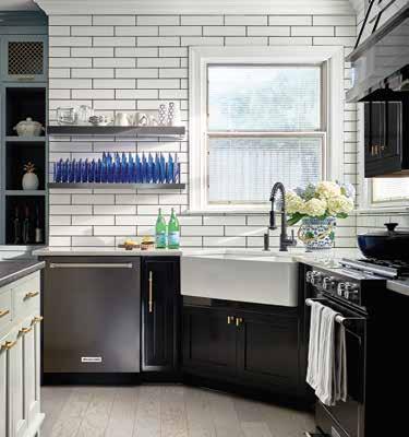 Countertops are white Carrara marble in a polished finish. The black range hood makes a bold statement in the room, with custom molding matching the custom motif on the kitchen island.