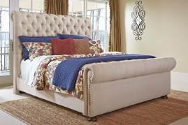 B662 Windville (Ashley Millennium HS Exclusive) Rolled top tufted upholstered bed has a light brown textured fabric and nail head trim and turned wood foot Beds available: King