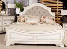 Traditional cottage bedroom in an antiqued two-tone finish featuring chipped white cases with distressed wood finished tops Tops feature oak veneers while case pieces are made