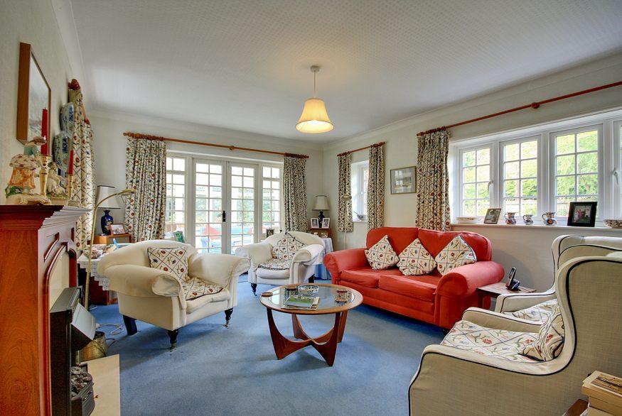 The sitting room is a lovely bright room with a triple aspect, windows to the front and rear, a fireplace with electric fire and a built in bookcase.