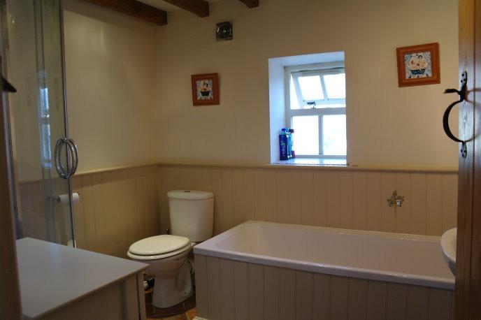 Extractor fan, double glazed, obscured window to side, room having half wood panelled walls with tiled shower cubicle and chrome heated towel rail.
