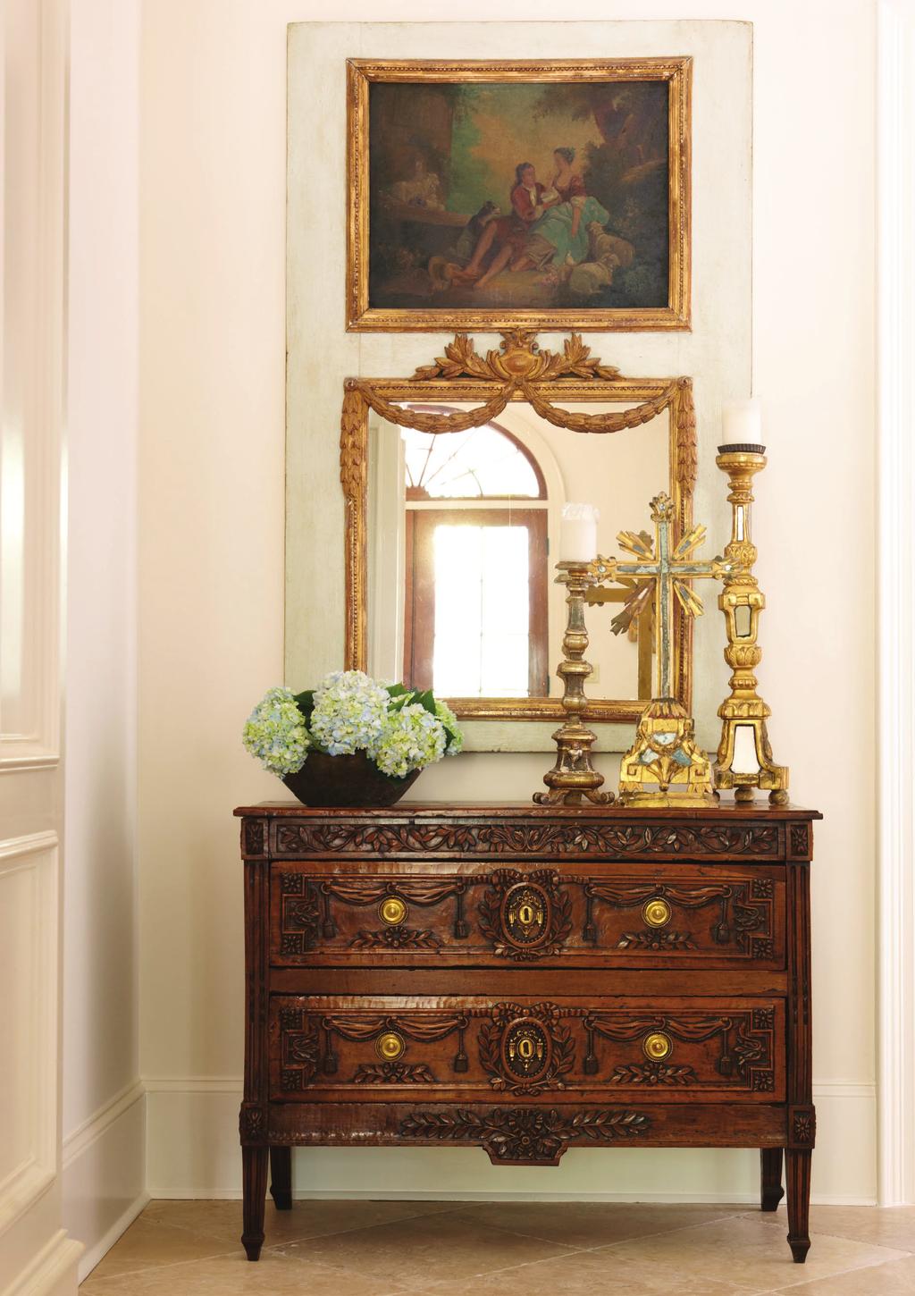 THIS PHOTO: In the foyer, a collection of 18th-century altar sticks and bois doré (gilded wood) mirrored crosses sit atop a Louis XVI walnut commode from a château near Cassis, France.