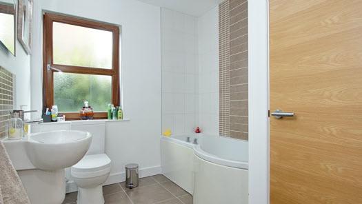 BATHROOM: White bathroom suite comprising panelled bath with thermostatically controlled shower over, wall mounted wash