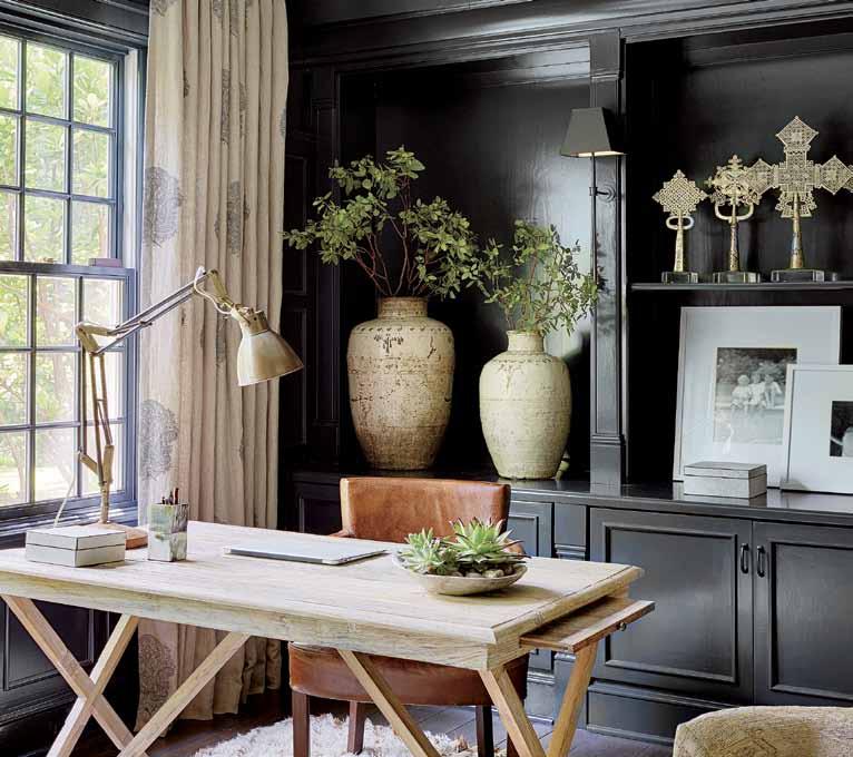 An oak desk and leather chair, both from Jayson Home, enhance the library walls featuring Benjamin Moore paint, while a Moroccan rug from Stark adds texture to the eclectic space.