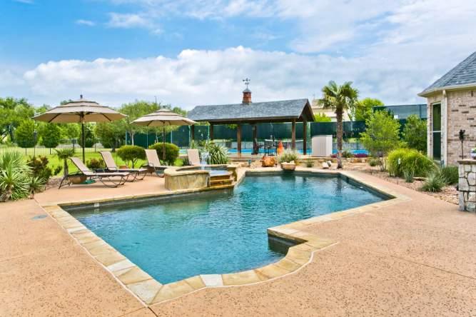The resort style oasis backyard features sparkling pool with diving rock