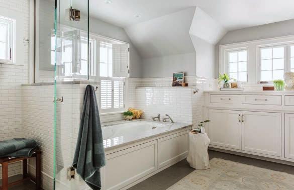 the panels on the tub surround match the custom cabinetry that provides storage and organization beneath the casement windows that, like the windows above the whirlpool tub, offer an
