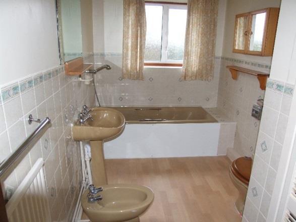 Ground Floor Bathroom comprising panelled bath with mixer tap and shower attachment. Patterned ceramic tile surround. Side elevation opaque double glazed window.