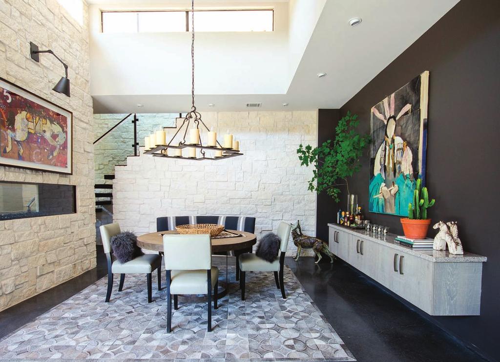 A double-sided fireplace with floating serving cabinet by Wood Mode frame the Lillian August dining table. Chairs and bench seating by Vanguard Furniture; custom sconce by L Design Group.