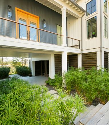 CHARMING FEATURES: Cast Stone Pavers along Modern Entry Deck Dwarf Papyrus and Native Grasses at Entry Custom-Designed Ipe Deck Home Built by