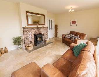 This well proportioned room has a Travertine tiled floor and a feature 'antique brickwork' fire surround with a timber mantle and flagstone hearth, housing a cast iron wood burning stove.