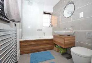 low level storage and low flush WC with concealed cistern. Shaver point. Tiled floor. Chrome ladder style heated towel radiator. Part tiled to the walls. Recessed down-lights to the ceiling.