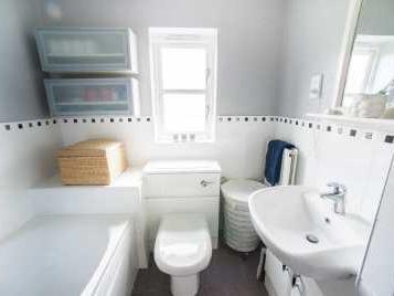 Bathroom White suite, low level wc, wash basin, bath with mixer tap, shower cubicle, radiator, window to rear, spotlights, shaver socket, tiled floor, extractor.
