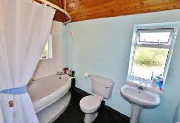 67m) Central heating radiator, part tiled walls, suite comprising coloured panelled corner bath with plumbed in shower, pedestal wash hand basin and low level wc.