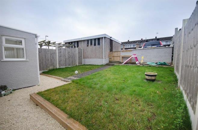 OUTSIDE FRONT Mainly laid to lawn displaying small established trees and shrubs, pathway leading to main entrance, wooden gate providing pedestrian access into rear garden.