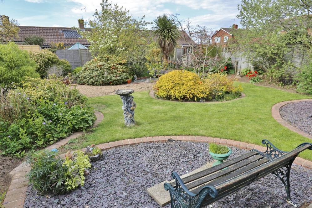 OUTSIDE The front garden is enclosed behind a low level brick wall with wrought iron double opening gates leading on to driveway and garage. The front garden is planted with various shrubs and bushes.