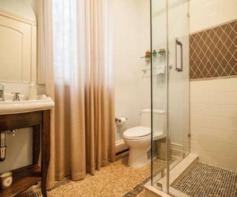 Full Bath: Mirror over French porcelain sink with Grohe faucet, window with draperies, commode, shower stall with hand held sprayer, and tile floor.