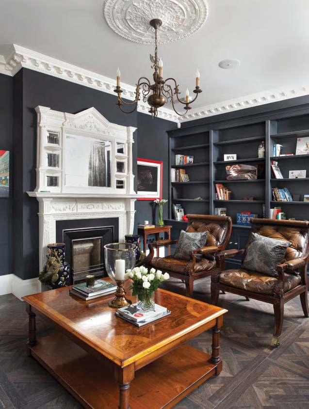in the library with walls painted in Farrow & Ball Railings giving bold contrast to the cornicing, ceiling rose and fireplace.