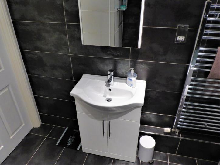co-ordinating contemporary light grey and black stone effect ceramic tiling to walls.