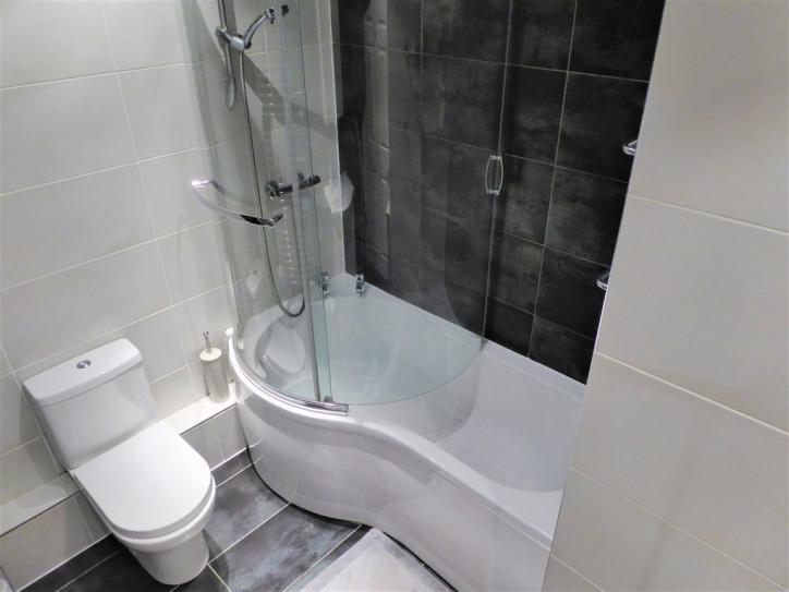 Close coupled WC with matching white soft closure seat and tiled boxed pipework. Chromed central heating towel rail. Chromed shaver point.