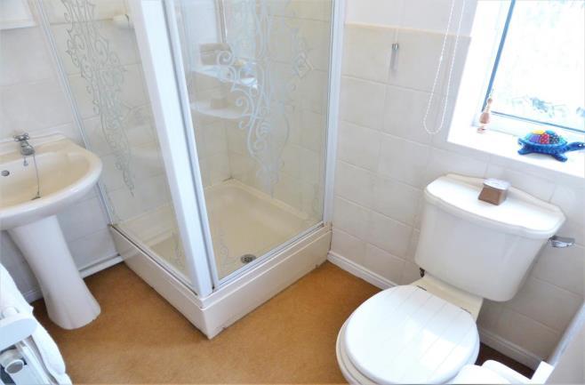 ENSUITE BATHROOM A bright and fresh shower room, neutrally tiled, comprising shower cubicle, pedestal sink,